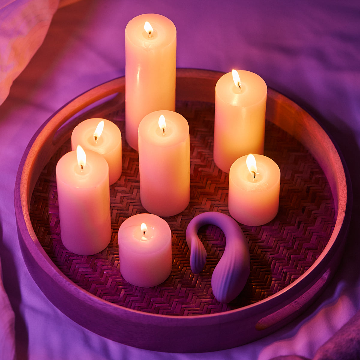 Velvet Rituals Eclipse couples massager placed beside lit candles, creating a warm, intimate atmosphere for partner play