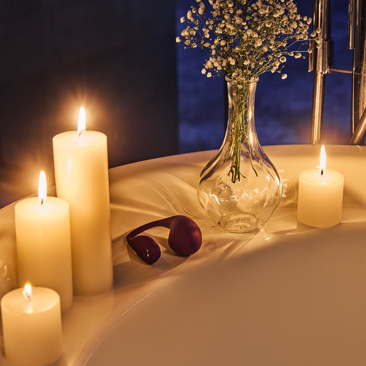 Velvet Rituals Naiomy wearable massager placed in a candle-lit bathtub setting for a relaxing, intimate self-care experience