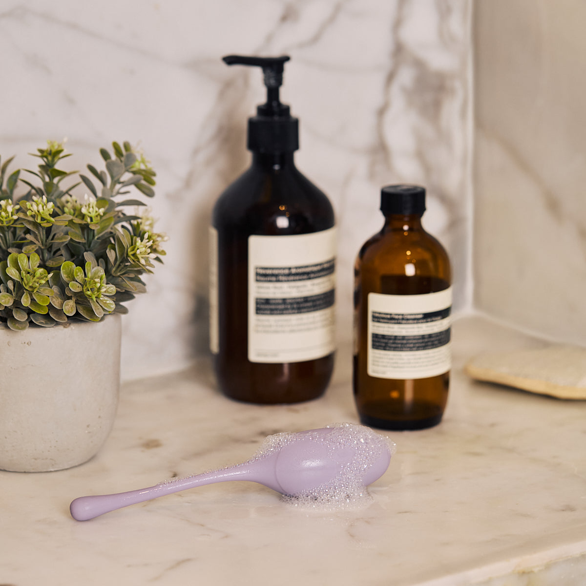 Velvet Rituals Pearl internal massager being gently cleaned on a marble countertop, highlighting its waterproof, non-porous, hygienic silicone design