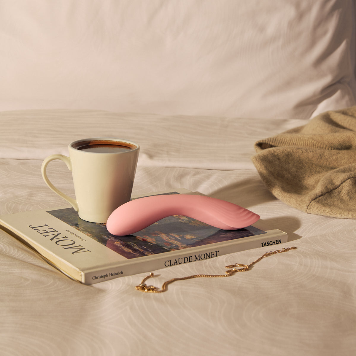 Velvet Rituals Ember internal massager placed in a cozy bedroom setting with a book and coffee, highlighting its calming, everyday relaxation use