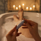 Velvet Rituals Pixie compact external pleasure device held in hand during a relaxing bath, highlighting waterproof design and soothing lifestyle use